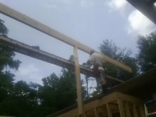 Carpenter setting a ridge beam over a new addition frame — Ice Dam Removal by Roofing Brothers in Highland Lake