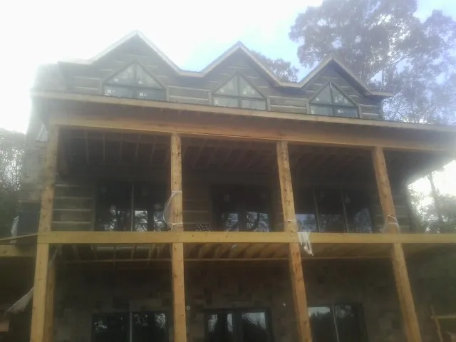 Dormers and porch framing on a large log home under construction — Roof Coating work by our crew in Highland Lake