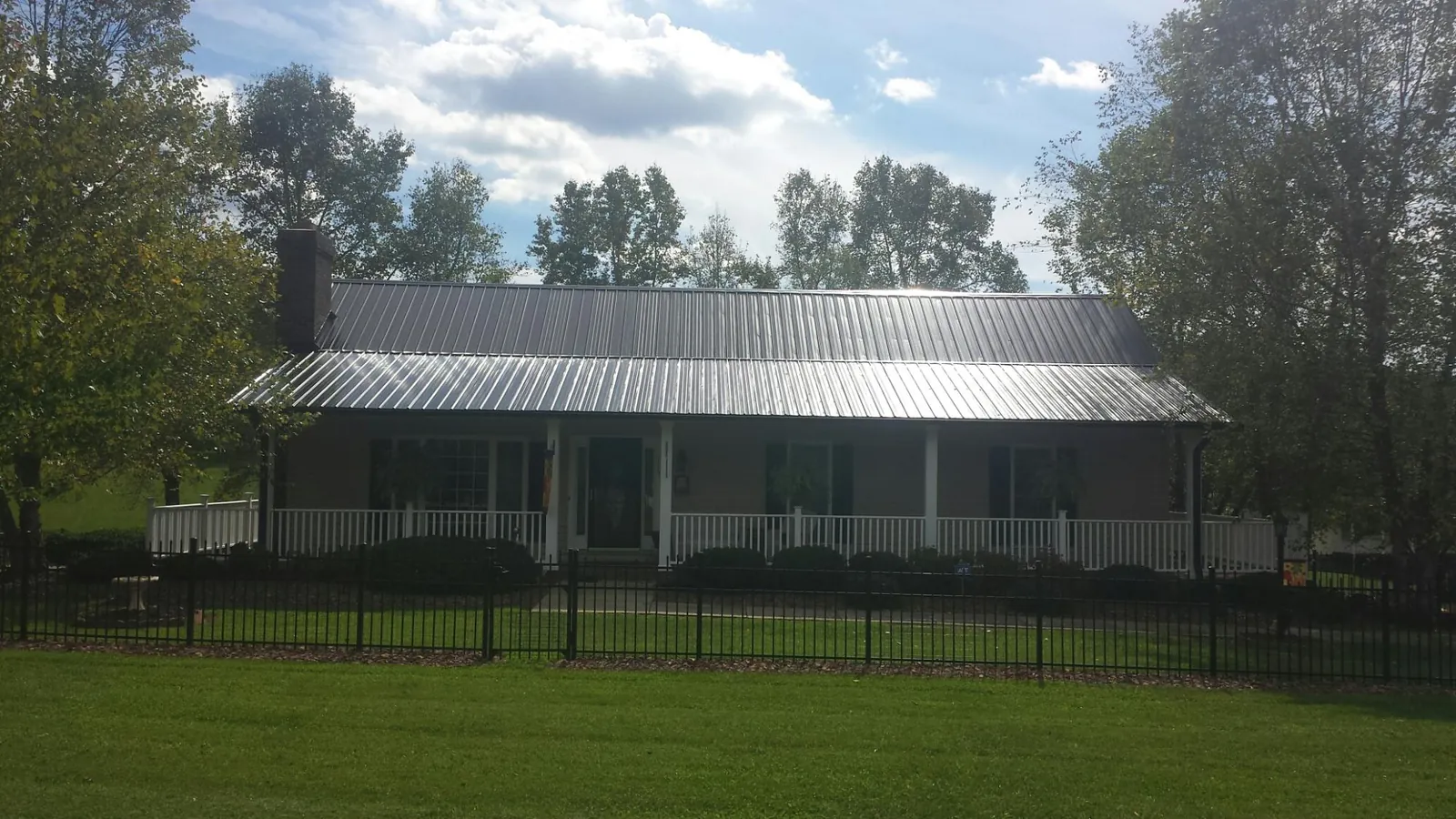 Gray metal roof on a brick ranch with a full width front porch — Gutter Guard Installation work by our crew in Highland Lake