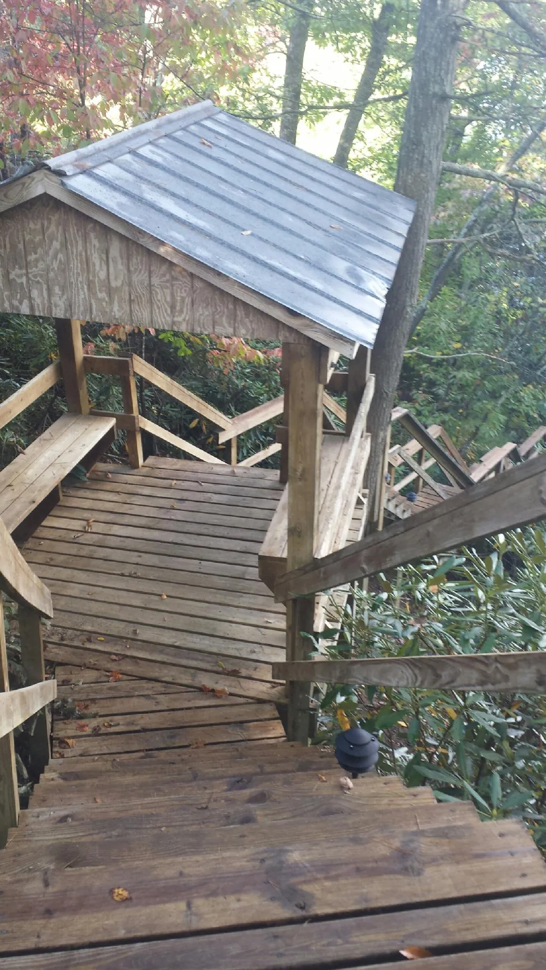 Metal roofed shelter over wooden steps on a wooded walkway — Skylight Repair & Installation work by our crew in Highland Lake