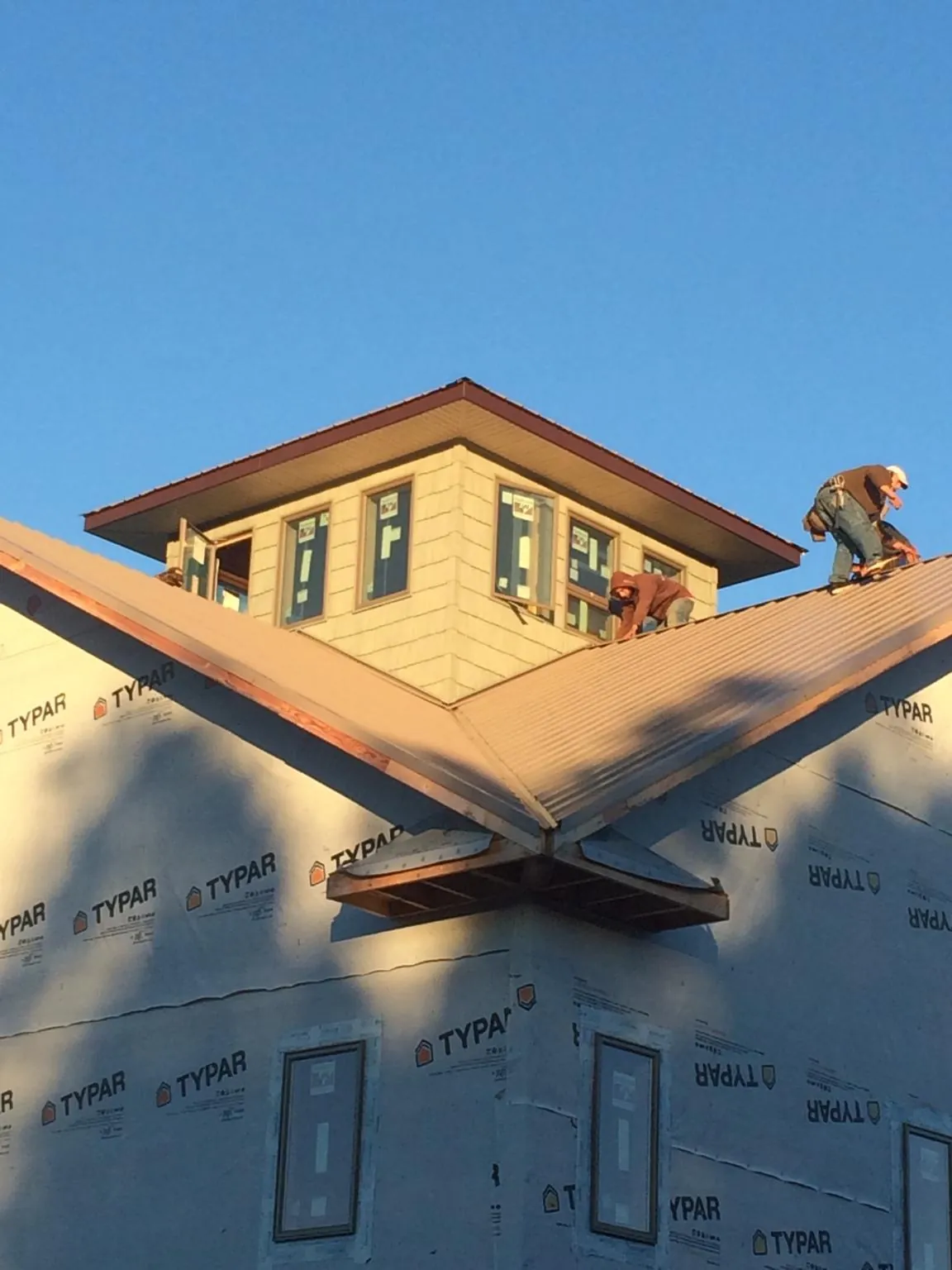 Roofers working around a rooftop cupola on a new metal roof at sunset — Roof Waterproofing in Highland Lake by Roofing Brothers